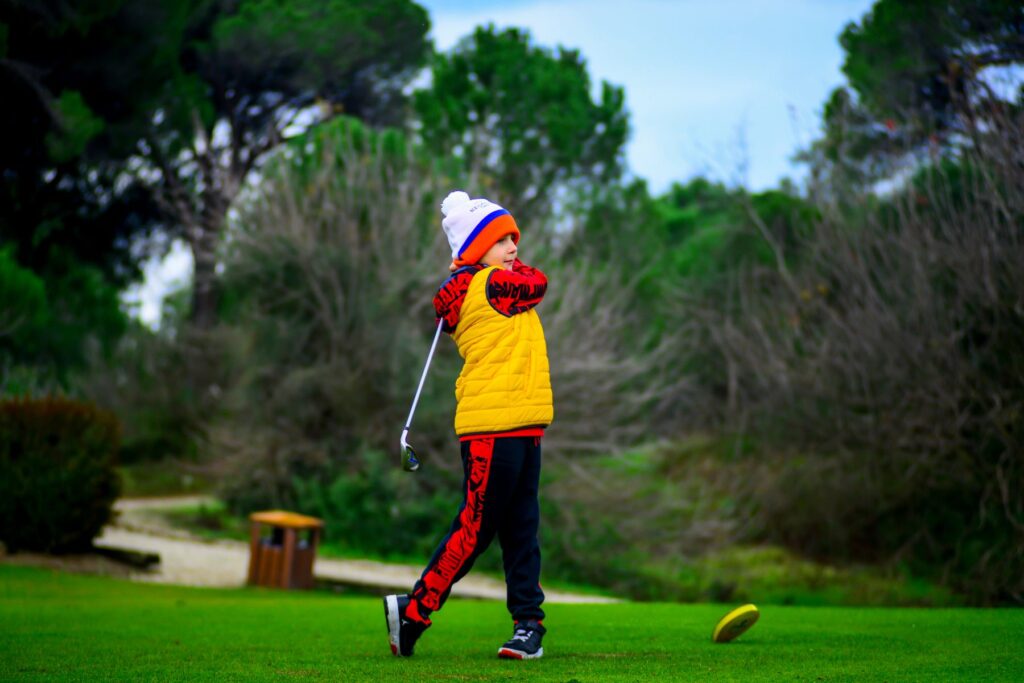 Child golfer swinging a club on a lush green golf course